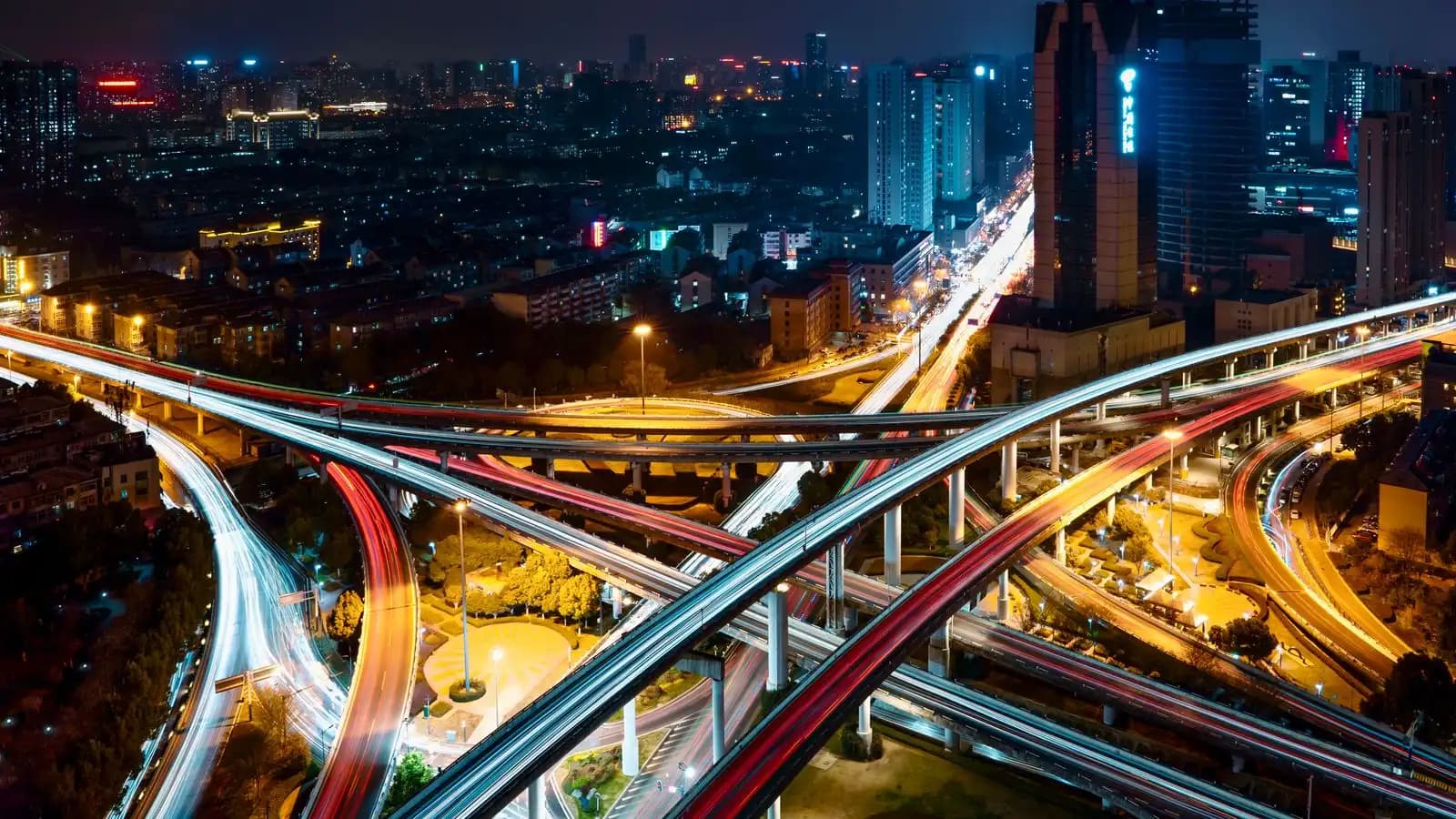 Aerial night view of a city highway interchange where many lit roads cross