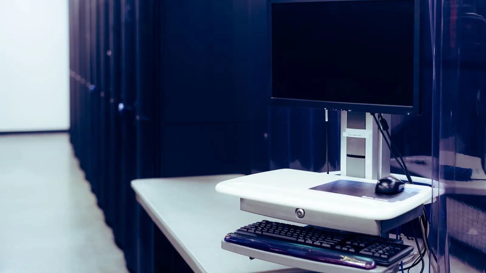 Monitor and keyboard on a console stand beside a row of server racks in a data centre
