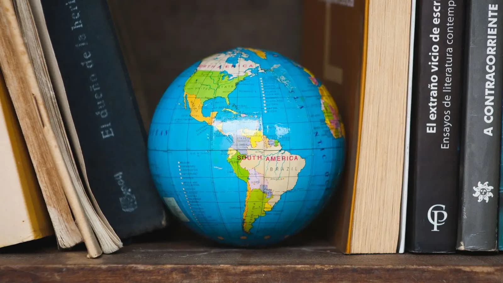 Desk globe between old books on a wooden shelf