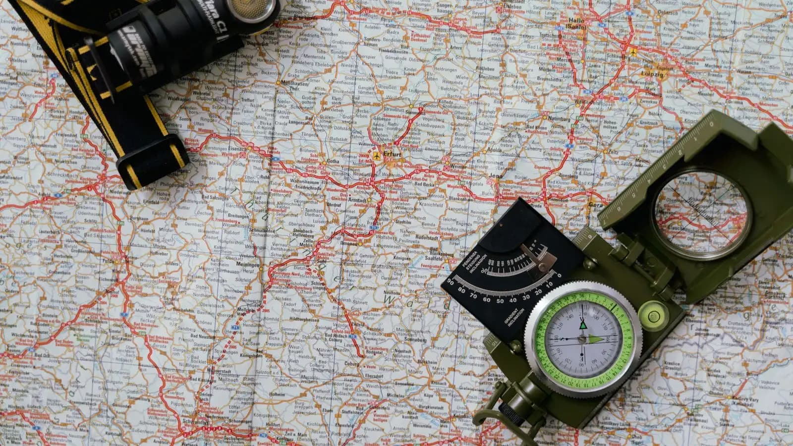 Road map seen from above with a compass and a flashlight laid on it