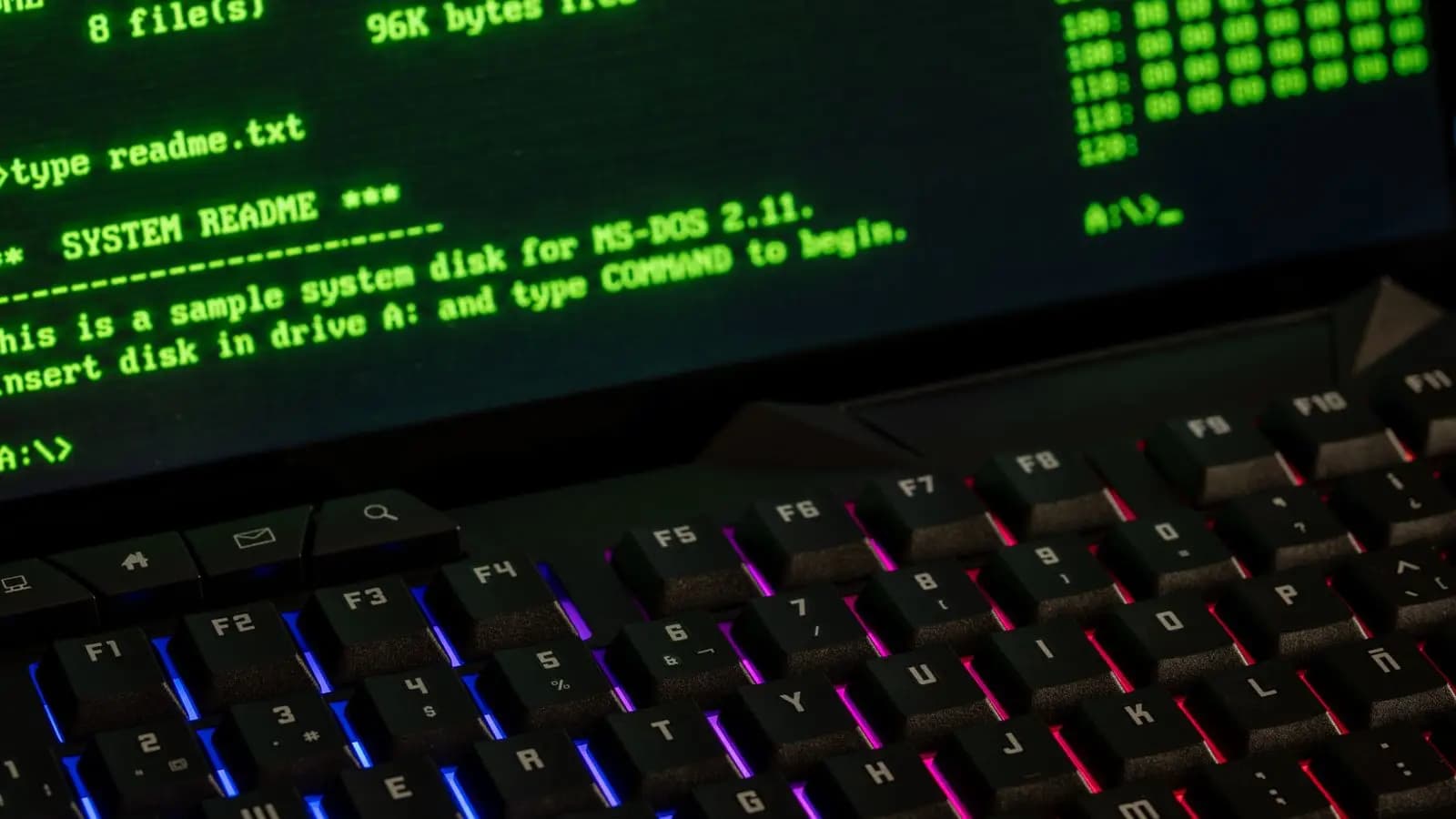 Computer screen showing green command-line text above a backlit keyboard