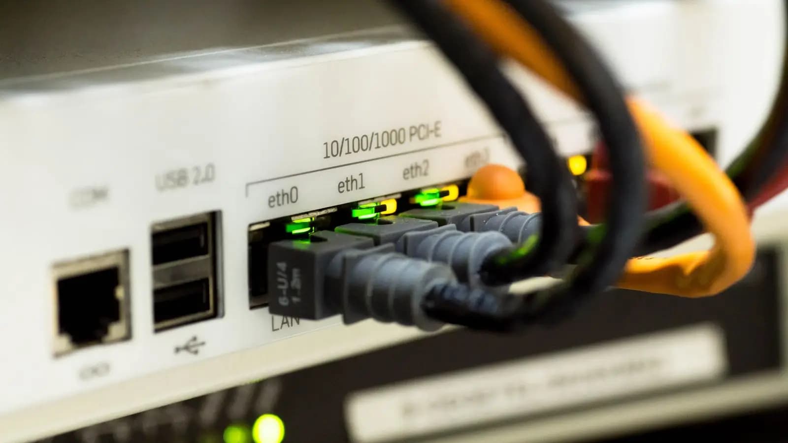 Ethernet cables plugged into the ports of a network switch with green link lights
